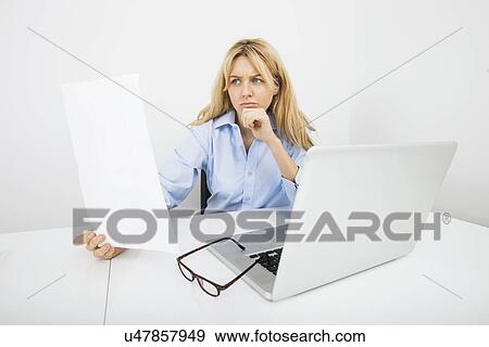 Stock Photo - Young businesswoman reading document in office. Fotosearch