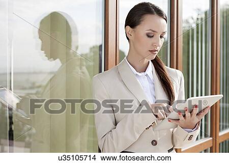 Young businesswoman using digital tablet against office building View Large Photo Image Picture - Young businesswoman using digital tablet against office building. Fotosearch