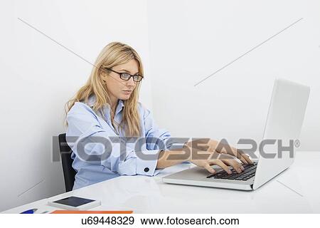 Young businesswoman using laptop at desk in office View Large Photo Image Stock Photo - Young businesswoman using laptop at desk in office. Fotosearch