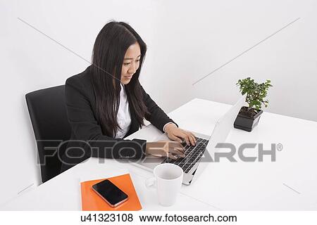 Young businesswoman working on laptop at office desk View Large Photo Image Stock Photo - Young businesswoman working on laptop at office desk. Fotosearch