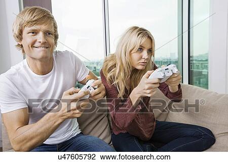 Young couple playing video game in living room at home View Large Photo Image Stock Image - Young couple playing video game in living room at home. Fotosearch