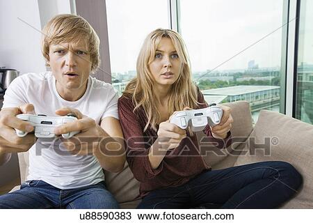 Young couple playing video game in living room at home View Large Photo Image Stock Image - Young couple playing video game in living room at home. Fotosearch