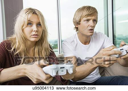 Young couple playing video game in living room at home View Large Photo Image Stock Image - Young couple playing video game in living room at home. Fotosearch