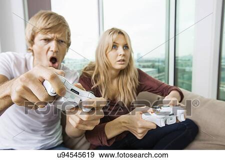 Young couple playing video game in living room at home View Large Photo Image Stock Photo - Young couple playing video game in living room at home. Fotosearch