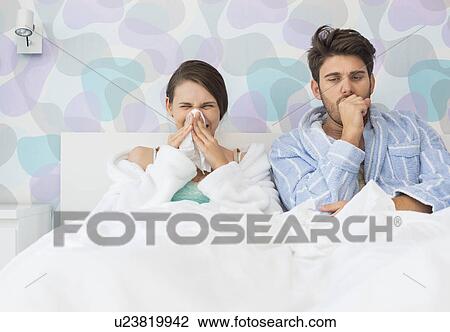 Young couple suffering from cold and flu in bed at home View Large Photo Image Stock Image - Young couple suffering from cold and flu in bed at home. Fotosearch