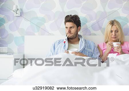 Young couple suffering from cold while relaxing in bed at home View Large Photo Image Stock Image - Young couple suffering from cold while relaxing in bed at home. Fotosearch