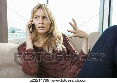 Young displeased woman talking on mobile phone at home View Large Photo Image Stock Photo - Young displeased woman talking on mobile phone at home. Fotosearch