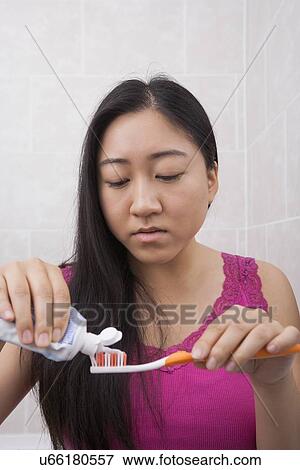 Young woman applying toothpaste onto toothbrush in bathroom View Large Photo Image Stock Photo - Young woman applying toothpaste onto toothbrush in bathroom. Fotosearch