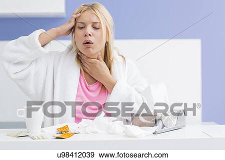 Young woman coughing while suffering from headache and cold in kitchen View Large Photo Image Stock Photo - Young woman coughing while suffering from headache and cold in kitchen. Fotosearch