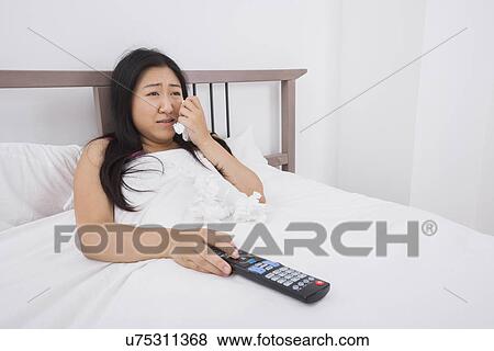 Young woman crying while watching TV in bed View Large Photo Image Stock Photo - Young woman crying while watching TV in bed. Fotosearch