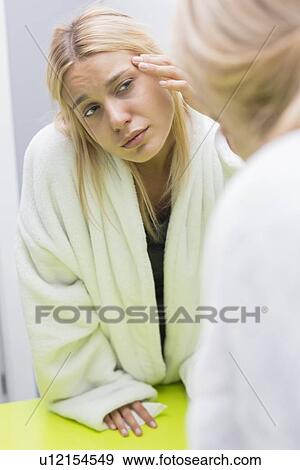Stock Photo - Young woman examining eye in mirror. Fotosearch