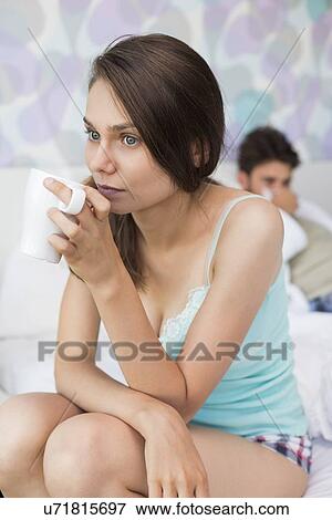 Young woman having coffee on bed with man lying in background View Large Photo Image Stock Photo - Young woman having coffee on bed with man lying in background. Fotosearch