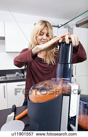 Young woman juicing carrots in kitchen View Large Photo Image Stock Photo - Young woman juicing carrots in kitchen. Fotosearch