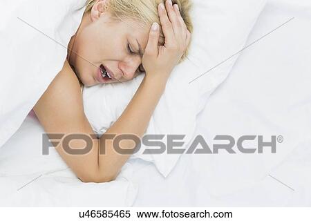 Young woman screaming while suffering from headache in bed View Large Photo Image Stock Photography - Young woman screaming while suffering from headache in bed. Fotosearch