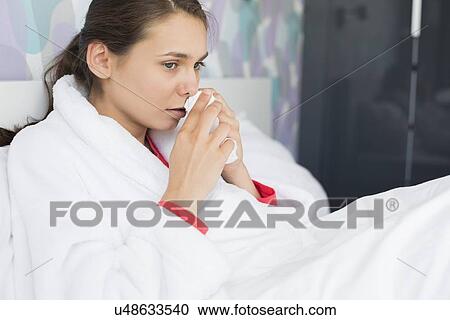 Young woman suffering from cold using tissue paper in bedroom View Large Photo Image Stock Image - Young woman suffering from cold using tissue paper in bedroom. Fotosearch