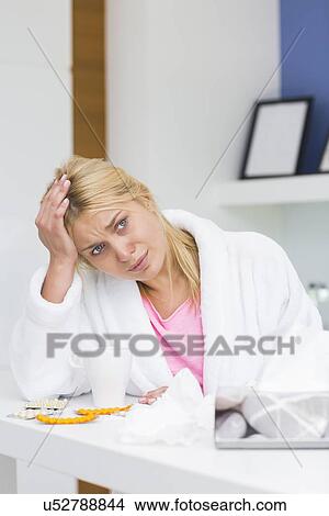 Picture - Young woman suffering from headache in kitchen. Fotosearch