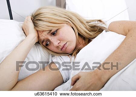 Stock Image - Young woman suffering from headache in bed. Fotosearch
