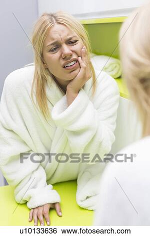 Stock Photograph - Young woman suffering from toothache while looking at mirror. Fotosearch