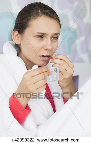 Young woman taking medicine in bedroom at home View Large Photo Image Stock Image - Young woman taking medicine in bedroom at home. Fotosearch