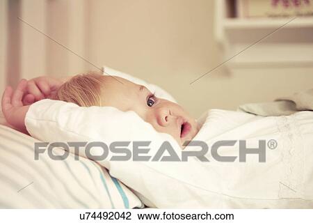 Baby girl lying in bed View Large Photo Image Stock Image - Baby girl lying in bed. Fotosearch