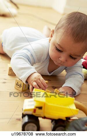Baby lying on front playing with blocks and truck View Large Photo Image Stock Photo - Baby lying on front playing with blocks and truck. Fotosearch