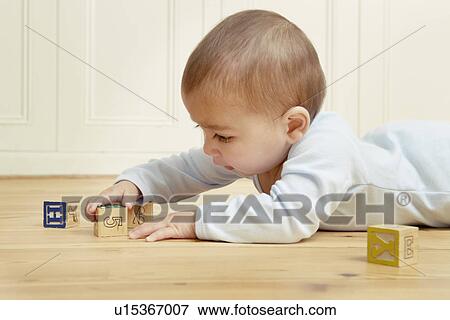 Baby lying on front playing with building blocks View Large Photo Image Stock Photo - Baby lying on front playing with building blocks. Fotosearch