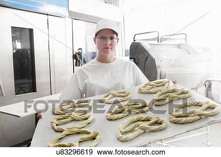 Stock Photo - Baker holding baking sheet of pretzels. Fotosearch