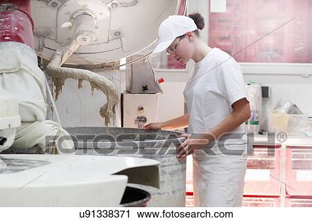 Stock Image - Baker looking into mixer. Fotosearch