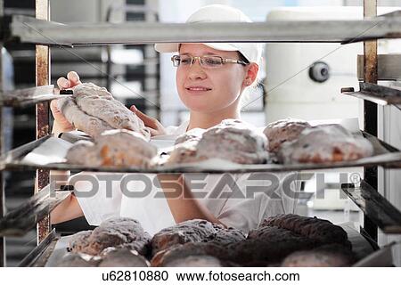 Stock Image - Baker putting bread dough on baking sheet. Fotosearch