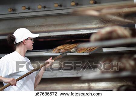 Baker putting bread on shelf View Large Photo Image Stock Image - Baker putting bread on shelf. Fotosearch