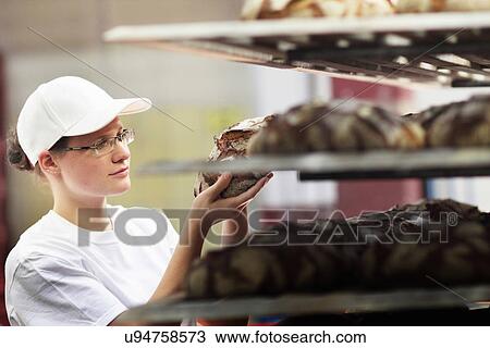 Stock Image - Baker putting bread on shelf. Fotosearch