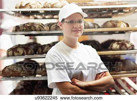 Stock Photography - Baker standing in front of bread on shelves with arms folded. Fotosearch