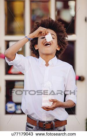 Boy eating confectionary outside shop View Large Photo Image Stock Image - Boy eating confectionary outside shop. Fotosearch