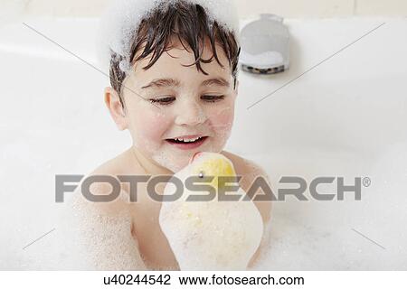 Boy in bath with bubbles on his head, holding rubber duck View Large Photo Image Stock Image - Boy in bath with bubbles on his head, holding rubber duck. Fotosearch
