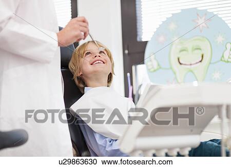 Stock Image - Boy in dentists chair having check up. Fotosearch