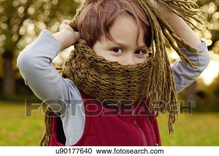 Stock Image - Boy in park, with scarf covering mouth. Fotosearch