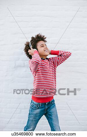 Boy on street happily listening to headphones View Large Photo Image Stock Image - Boy on street happily listening to headphones. Fotosearch