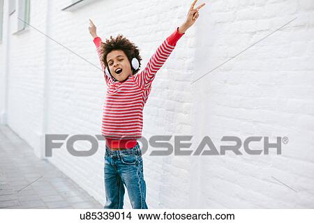 Boy on street with arms out listening to headphones View Large Photo Image Picture - Boy on street with arms out listening to headphones. Fotosearch