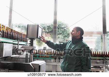 Brewery worker operating bottling machine View Large Photo Image Stock Photo - Brewery worker operating bottling machine. Fotosearch