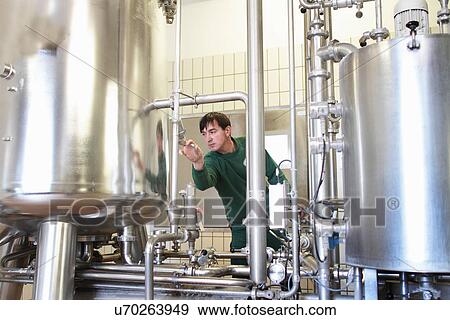 Brewery worker operating machine View Large Photo Image Stock Photo - Brewery worker operating machine. Fotosearch