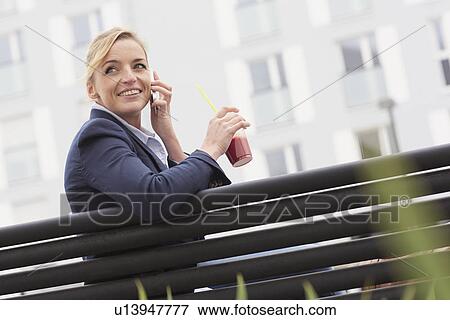 Stock Photo - Business woman having lunch break on park bench. Fotosearch