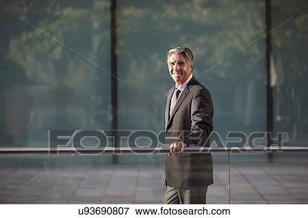 Businessman holding railing View Large Photo Image Stock Photo - Businessman holding railing. Fotosearch