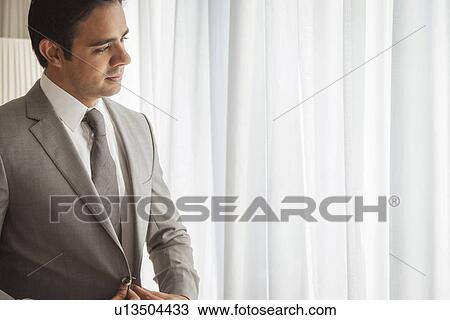 Stock Image - Businessman looking out of window. Fotosearch