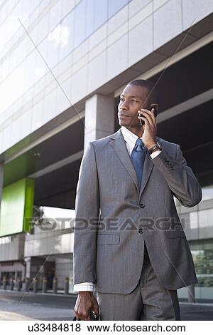 Businessman standing outside making phone call View Large Photo Image Stock Photo - Businessman standing outside making phone call. Fotosearch