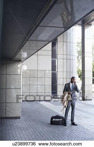 Businessman standing outside with bag and coat View Large Photo Image Stock Photograph - Businessman standing outside with bag and coat. Fotosearch