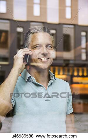 Stock Photo - Businessmen making phone call, view through window. Fotosearch