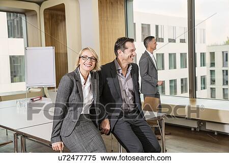 Businesspeople sitting on conference table View Large Photo Image Stock Photography - Businesspeople sitting on conference table. Fotosearch