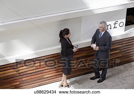 Businesspeople standing having conversation View Large Photo Image Picture - Businesspeople standing having conversation. Fotosearch
