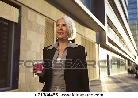 Businesswoman carrying hot drink View Large Photo Image Stock Photography - Businesswoman carrying hot drink. Fotosearch