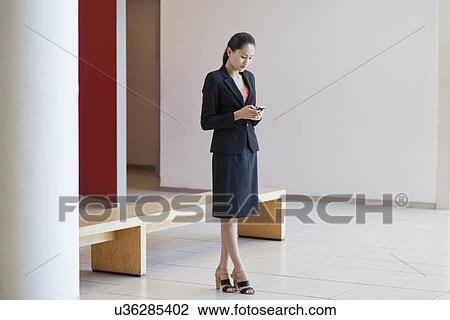 Businesswoman in waiting area of office, using smartphone View Large Photo Image Stock Image - Businesswoman in waiting area of office, using smartphone. Fotosearch